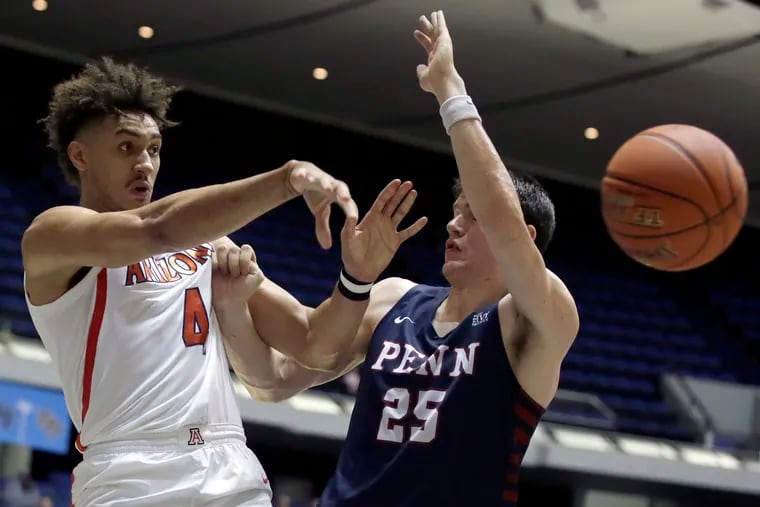 Arizona center Chase Jeter (left) passes the ball away from Penn's AJ Brodeur during the first half of their semifinal matchup at the Wooden Legacy tournament in Anaheim, Calif.