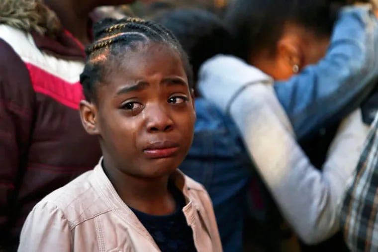 A girl (top) cries as family, friends and neighbors (above) gather on Wallace Street near 38th in Mantua for a vigil for 11-year-old Jamara Stevens, who cops say was accidentally shot by her 2-year-old brother, who found a loaded gun in the master bedroom.