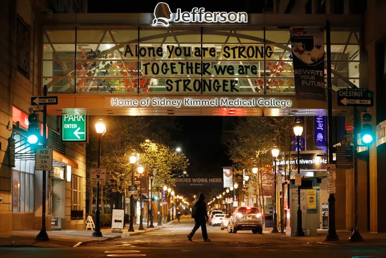 A sign pieced together and posted in the walkway, over South 10th Street, to Thomas Jefferson University Hospital reads “Alone you are STRONG TOGETHER we are STRONGER.”