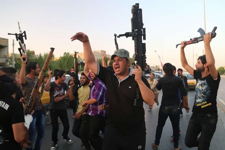 Shiite tribal fighters , mobilized by a call from their senior cleric, raise their weapons and chant slogans in Basra, southern Iraq. NABIL AL-JURANI / Associated Press