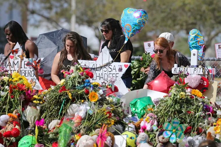 In this Feb. 25, 2018 photo, mourners bring flowers as they pay tribute at a memorial for the victims of the shooting at Marjory Stoneman Douglas High School, in Parkland, Fla. The community is focusing on suicide prevention programs after two survivors of the Florida high school massacre there killed themselves this month.