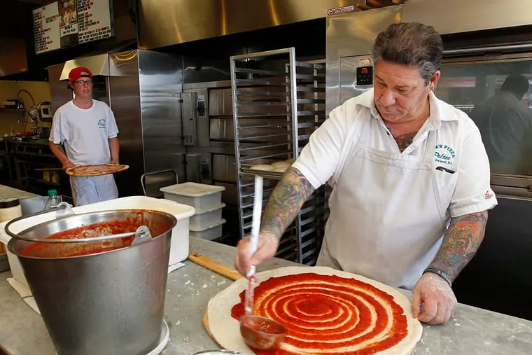 Anthony Spera ladles sauce on dough as he prepares a pizza for baking at Sam’s Pizza Palace in Wildwood. (Michael Bryant/Staff Photographer)