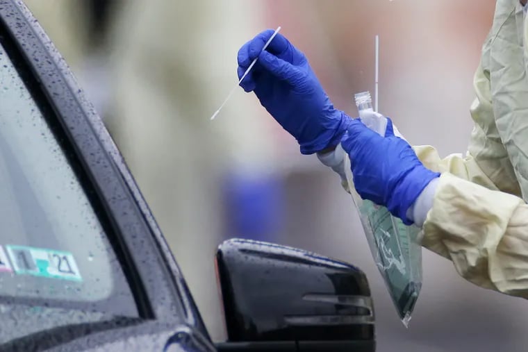 A medical worker collects samples from individuals who signed up for "drive-through testing" for the coronavirus at a Penn Medicine site in West Philadelphia on March 17, 2020.