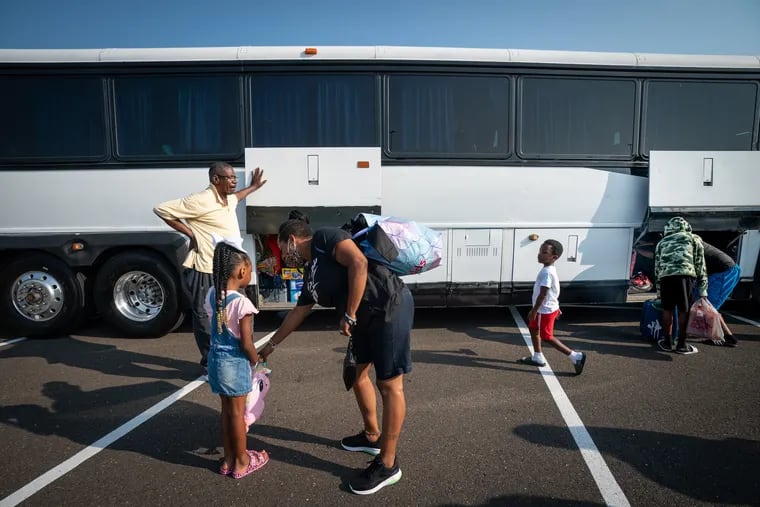 Families prepare to board the bus for a three-day retreat for Philadelphia children impacted by gun violence, in the parking lot of the Franklin Mills Mall last month.