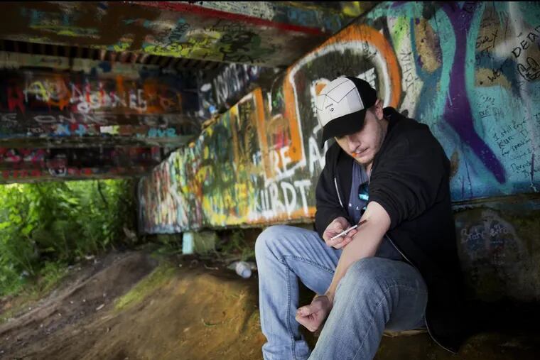 An addict injects heroin under a bridge at Kurt Cobain Memorial Park in Aberdeen, Wash.