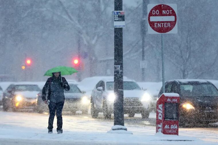 File Photo: A pedestrian braves the snow with an umbrella near 23rd and Spring Garden streets as snow falls on Dec. 15