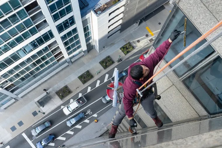 Jenkintown Building Services window washer Giovanni Funes cleaning the view for office workers at Commerce Square at 20th and Market Streets.