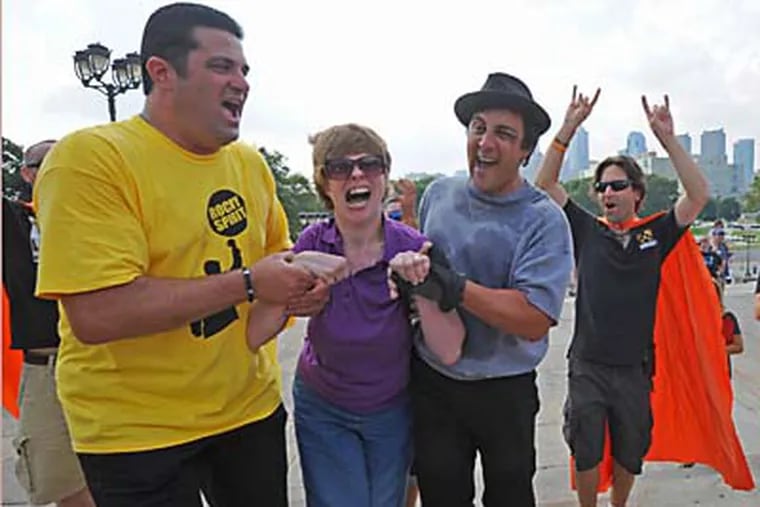 Glenda Hyatt, who has cerebral palsy, climbs the steps of the Philadelphia Museum of Art on July 28, 2012 with an assist from the Wish Upon a Hero Foundation.   In this photo, Felice Cantatore, left; and Sylvester Stallone impersonator Mike Kunda give her a hand.  APRIL SAUL / Staff Photographer
