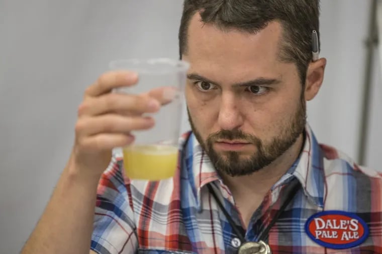 Ryan Dunnavant, director of quality control for Oskar Blues Brewery, and a judge for the competition, eyes the color and consistancy of an entrant in the Can Beer Category of this year's ninth annual Brewvitational competition for local beer on May 2, 2018 at the Reading Terminal Market.