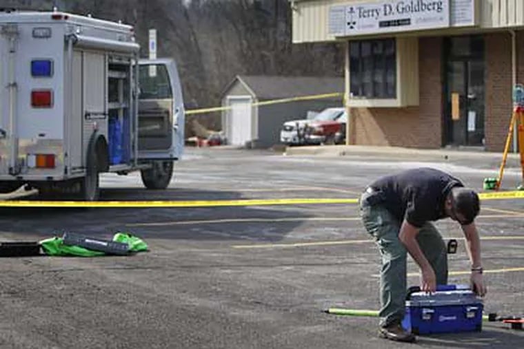 Bucks County detective Martin McDonough, right, works at the scene where an unidentified lawyer was shot in the parking lot in Gateway Shopping Center today. (David Maialetti / Staff Photographer)