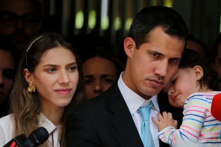 Opposition National Assembly President Juan Guaido, accompanied by his wife Fabiana Rosales and his 20-month-old daughter Miranda, listens to a reporter's question during a news conference outside their apartment, in Caracas, Venezuela, Thursday, Jan. 31, 2019. Guaido said security forces showed up at their home in an attempt to intimidate him. "The dictatorship thinks it can intimidate us," Guaido said.