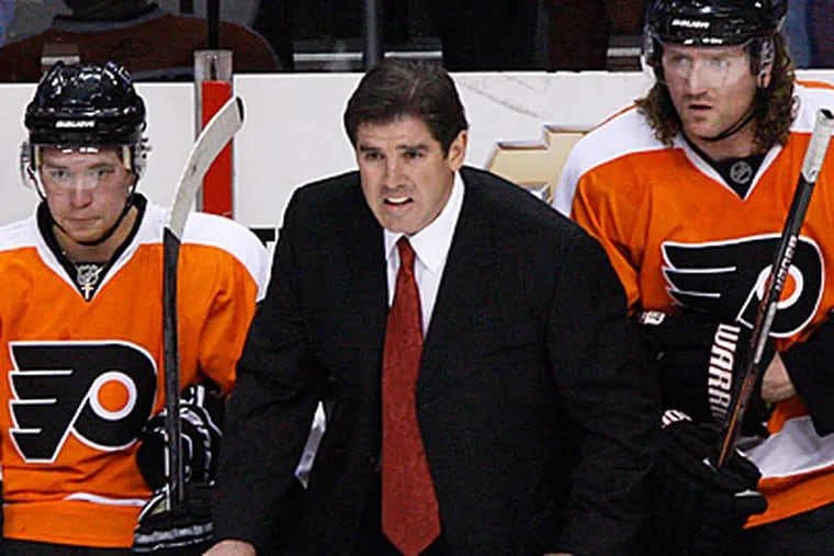 Philadelphia Flyers coach Peter Laviolette, center, watches from the bench in the first period of an NHL hockey game against the Capitals. (AP Photo/Matt Slocum)
