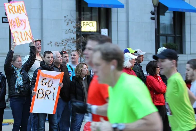 Spectators hold signs during the Gore-Tex Philadelphia Marathon.