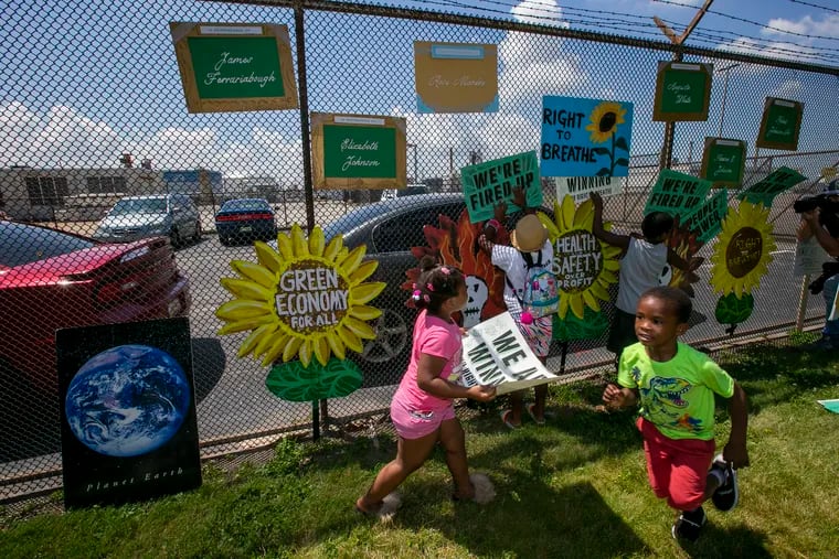 Young children hang signs at the former PES refinery before the start of a protest from Philly Thrive and S. Philadelphia residents at Passyunk Ave and 28th St. on June 22, 2020, the day after the one-year anniversary of the refinery explosion.