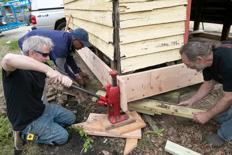 Darrell Williams (left), Owen Donnelly (center) and Jack Abgott prepare the wooden firehouse building to be moved into its new home inside the adjacent Relief Fire Co. in Mount Holly.