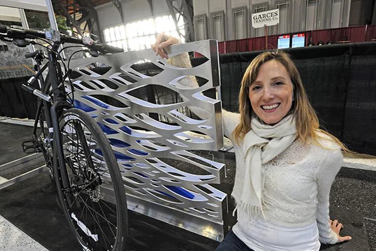 Juliet Whelan sits with the bike rack she designed and named "Koi," for the Bicycle Coalition of Greater Philadelphia competition at the Philadelphia Flower Show on Friday, Feb. 28, 2014. (April Saul / Staff Photographer)