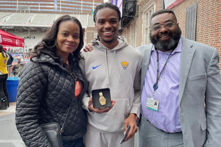 Pitt's Devin Nugent (center) celebrates with his mother Kimberly (left) and father Errol (right) after winning the Penn Relays college men's 400-meter hurdles title.