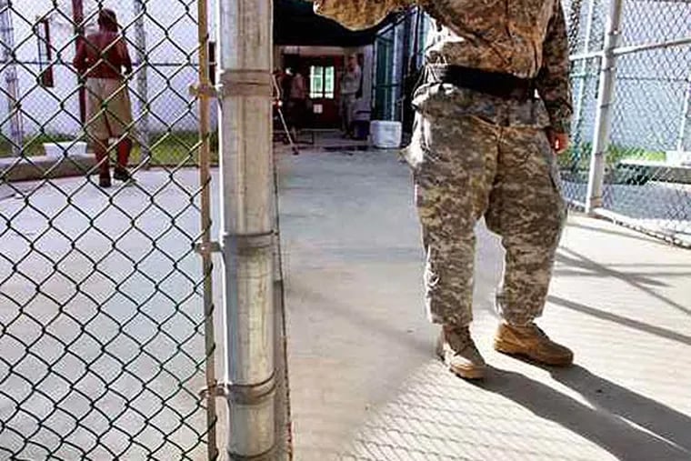 A guard stands near a fence as a Guantanamo detainee, (left) jogs inside the exercise yard at the detention center at the U.S. Naval Base in Guantanamo Bay, Cuba. (FILE)