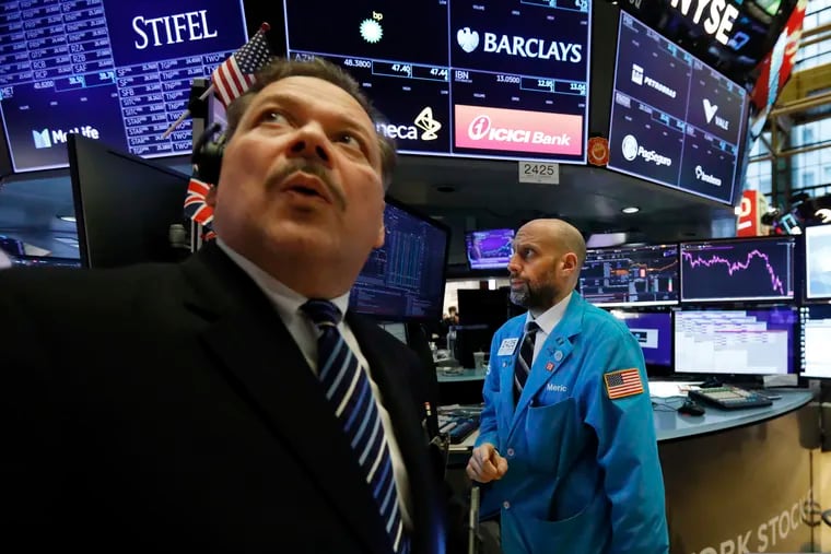 Trader John Santiago (left) looks at the numbers as he works on the floor of the New York Stock Exchange on Friday.