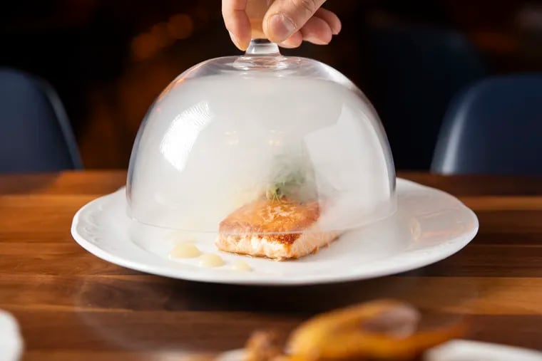 Salmon is served beneath a glass dome filled with smoke at Bar Lesieur, located at 1523 Sansom St. in Center City.