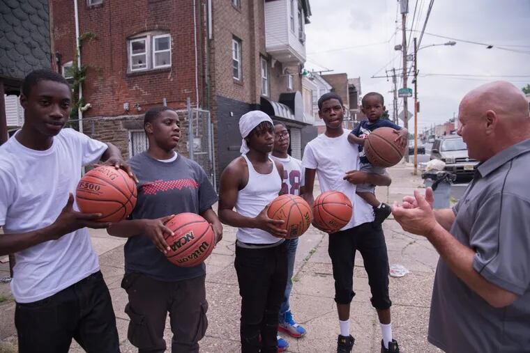 Mike Gibson (right) speaks with (from left) Deheim Smith-Myers, Tatiana Nixon, Tyrik Acres, Jamil Osborne, John Harper, and Matthew John Jones, age 2, at the corner of 59th and Kingsessing streets. Gibson gave the group five new basketballs.
