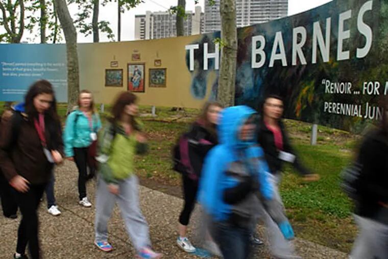 Passersby create an impressionist blur as they walk past the construction site for the Barnes Foundation on the Parkway. ( Tom Gralish / Staff Photographer )