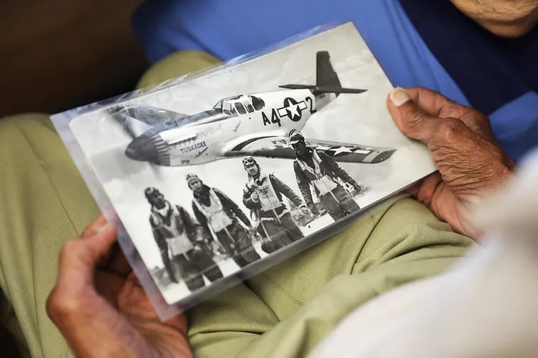 Melvin Frisby, 90, Sicklerville, a Tuskegee Airman, volunteers at the Camden County Senior Center, serving lunch to his peers. Frisby is holding a picture of him (far right) in and fellow pilots during the Korean War in the Pacific.