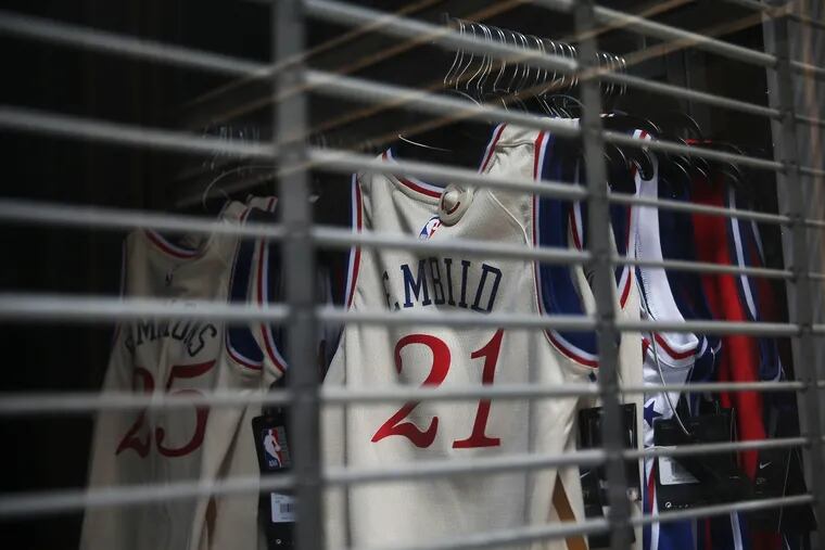 Jerseys of Sixers stars Ben Simmons and Joel Embiid are pictured behind a metal grate at the temporarily closed Macy's in Center City Philadelphia on Thursday, April 23, 2020. It is unclear when or if the NBA will finish its season due to the coronavirus pandemic.