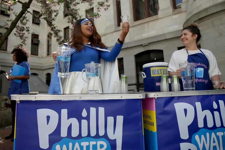 Maura Jarvis,community outreach worker for the Water Department, is dressed as “Water Woman” as she encourages people in the City Hall courtyard to try a sample of city water during a promotional campaign.