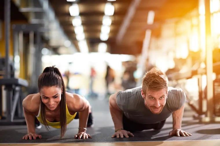 Photo shows couple doing pushups in gym. Delaware Valley Consumers’ Checkbook says most people can save money and meet all their fitness and recreation needs without joining private fitness clubs.