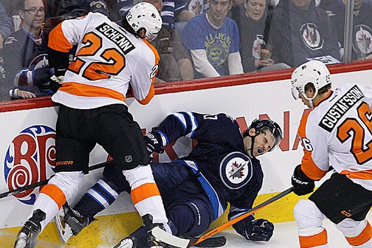 The Jets' Eric Tangradi is dumped by the Flyers' Luke Schenn as Erik Gustafsson picks up the loose puck. (John Woods/The Canadian Press/AP)