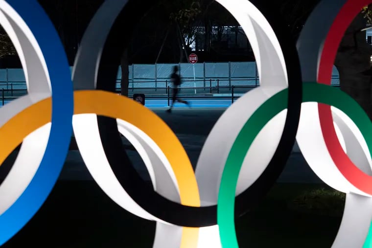 A man jogs past the Olympic rings in Tokyo.