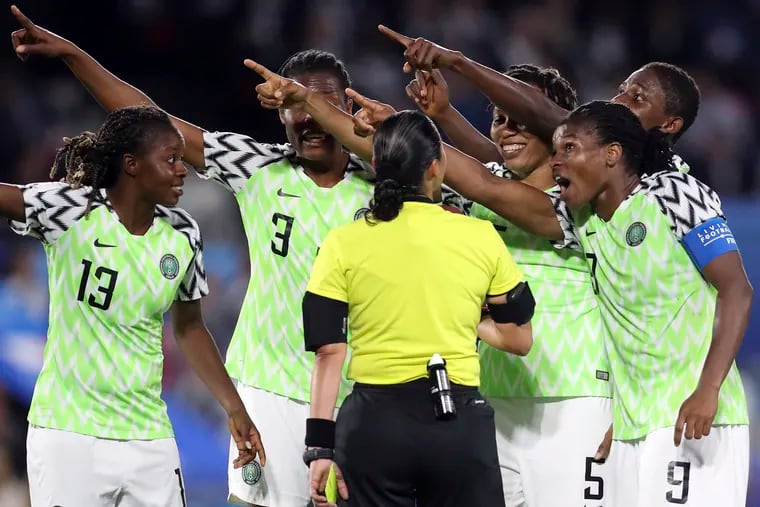 Nigerian players point toward the electronic screen as they protest a yellow card and a penalty awarded against their goalkeeper, Chiamaka Nnadozie.
