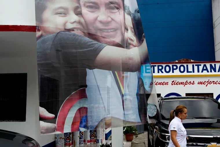 A banner of presidential candidate Mario Estrada Orellana, with the National Change Unit (UCN) party, hugging children hangs outside his party's headquarters in Guatemala City, Thursday, April 18, 2019. Estrada Orella, 58, was arrested Wednesday in Miami on drug and weapons charges, accused of plotting to assassinate political rivals and let drug dealers use Guatemala's ports and airports. (AP Photo/Moises Castillo)