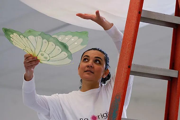 Blanca Munoz puts a butterfly into a ceiling draping during preparations for a quinceanera party in a banquet hall. Munoz, a recent graduate of the kennett Square Latino Entrepreneurship program, recently started a new business in planning events that focus on Latino celebrations. ( MICHAEL S. WIRTZ / Staff Photographer )