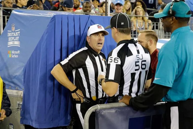 Referee John Hussey talks with side judge Allen Baynes outside the review booth during a 2016 NFL game. Fans in Philadelphia that say they watched less football last season blamed it on the delays in gameplay caused by penalties and reviews.