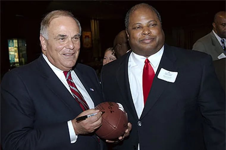 Gov. Ed Rendell (left) autographs a football while speaking with Robert Stinson Jr., of Life's Good, Inc., at a chamber of commerce event in 2008.  (File photo / Jules Vuotto Photography)