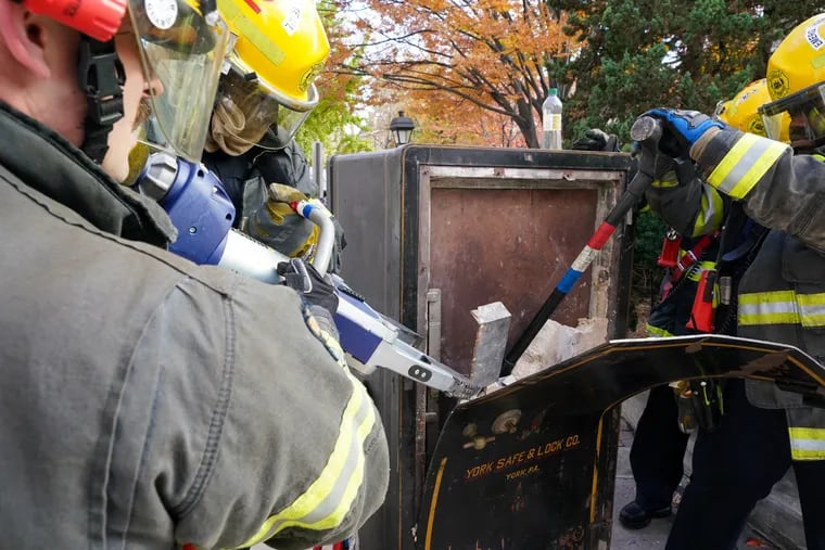 Philadelphia firefighters with Ladder 2 use the jaws of life to pry open the first layer of a safe discovered at the Old Pine Community Center in Society Hill.