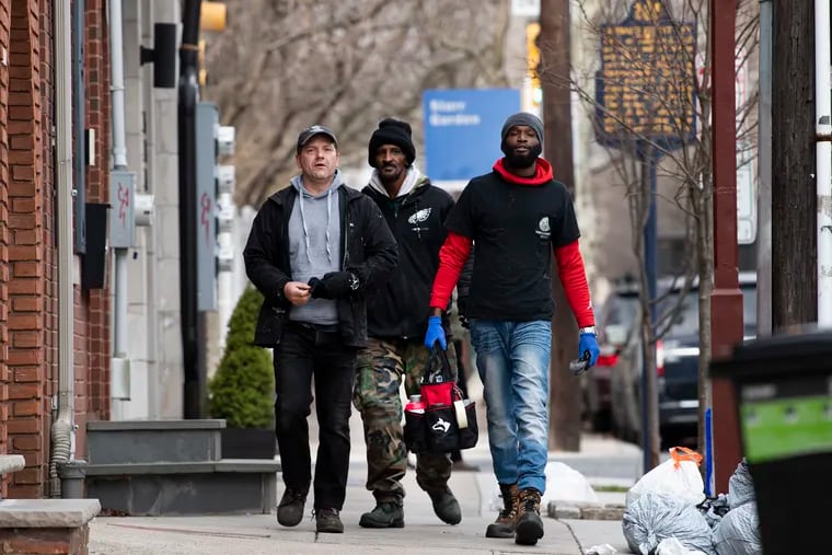 Todd Kelley (left), owner of Graffiti Removal Experts, and employees Wayne Robinson (center) and Steven Robinson search the streets of Old City for illegal graffiti and stickers, which they'll remove.