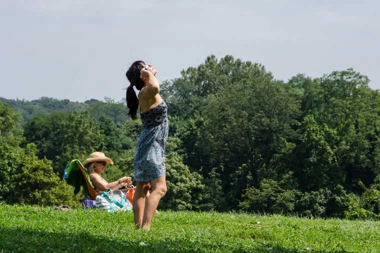 Nicole Mclane watches the beginning of the eclipse through her special solar eclipse glasses early Monday afternoon at Belmont Plateau. JOY LEE / STAFF PHOTOGRAPHER
