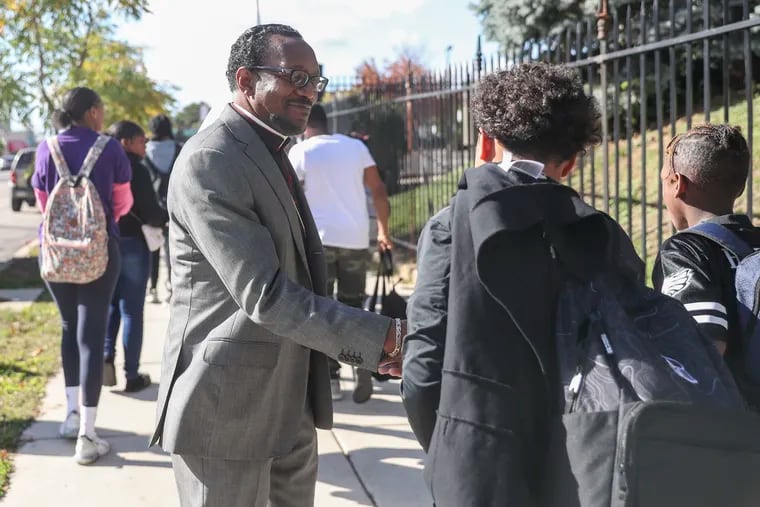 Bishop J. Louis Felton of the Mt. Airy Church of God In Christ hands out flyers of his upcoming Town Hall event to students from across the street of Wagner Middle School in Philadelphia on Tuesday, Oct. 18, 2022. Bishop Felton is leading a call to get local churches more involved in violence prevention, including reaching out to the youth.