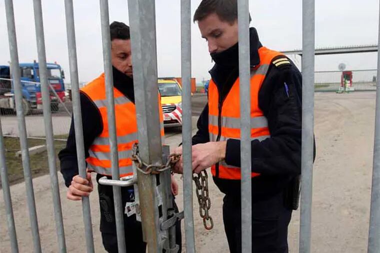 Police officers lock a gate that leads to a Brussels airport tarmac. Robbers made a holein a fence there to snatch $50 million worth of diamonds from a Swiss-bound plane. (Associated Press)