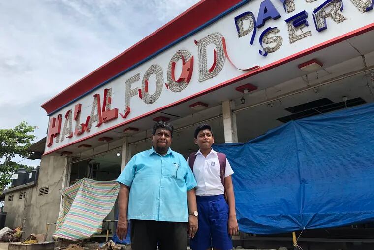 M. M. Mohomed Indhas with his son outside his restaurant, a 24-hour eatery called the New Fawz Hotel. Anti-Muslim rioters attacked the premises on May 13. MUST CREDIT: Washington Post photo by Joanna Slater