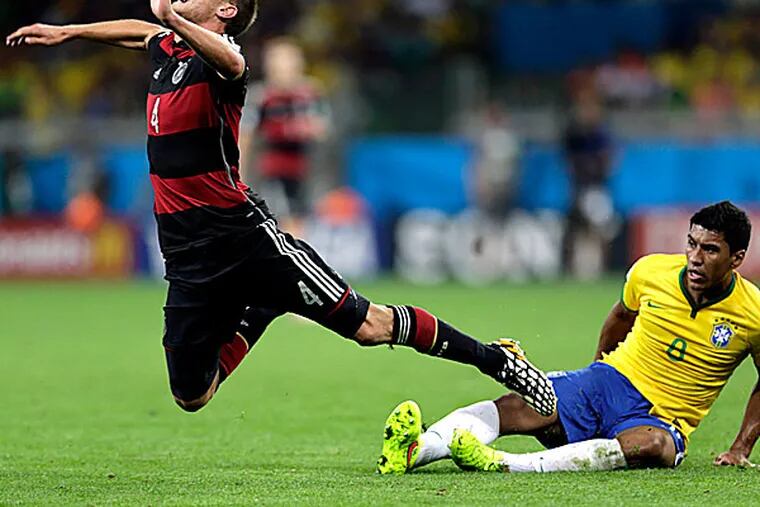 Germany's Benedikt Hoewedes is tripped by Brazil's Paulinho.