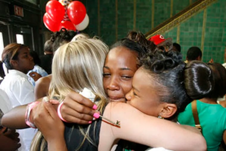 Students Christina Brown (center) and Erica Hall (right) embrace teacher Ajaka Roth after the promotion ceremony.