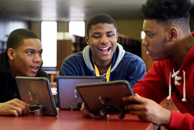 Chester High School girls basketball team manager, junior Kori Rochester (left) works with boys basketball players freshman Karell Watkins and sophomore Zahmir Carrill (right) during after school coding class.