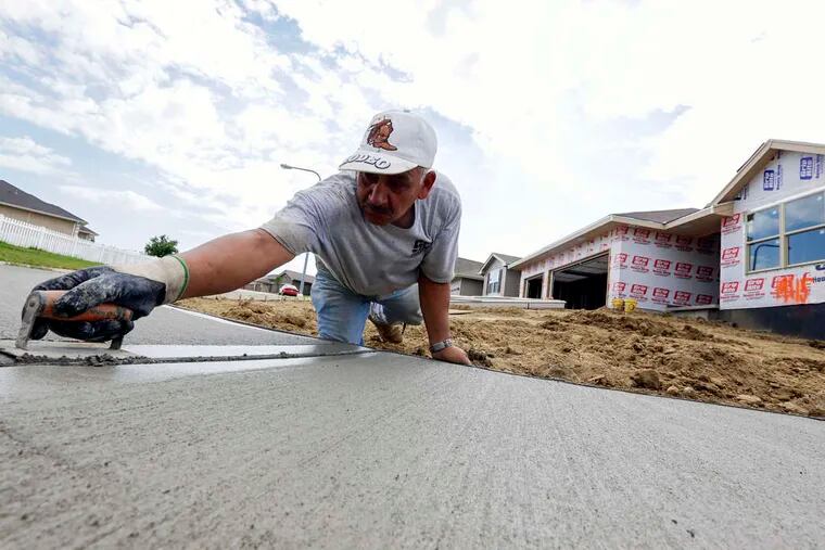 A worker finishes a sidewalk in front of a new home in Omaha, Neb. The Fed's action this week could lead to higher interest rates on mortgages.
