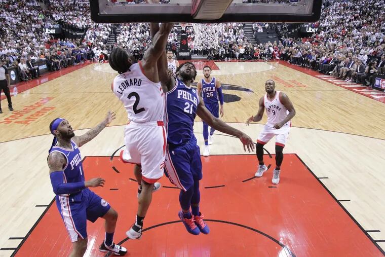 Kawhi Leonard, #2, 2nd from left, of the Raptors dunks over Joel Embiid, center, of the Sixers during the 2nd half of their NBA Eastern Conference semifinal game at the Scotiabank Arena in Toronto on May 7, 2019.