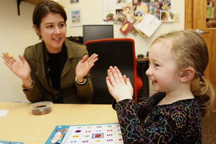 Sarah Gross, 4, right, claps out the syllables in words as she works with Cara Luliano, a speech and language pathologist at the Clarke School in Bryn Mawr. (Charles Fox / Staff Photographer)