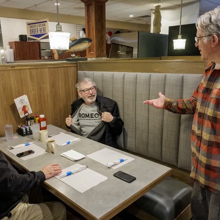 At Hymie's in Merion Station, John Makransky (standing), a patron since he was 6 years old, is joined by fellow R.O.M.E.O. (Retired Old Men Eating Out) Club member Larry Finkelstein (flashing a club shirt) and Brad Sinoff.